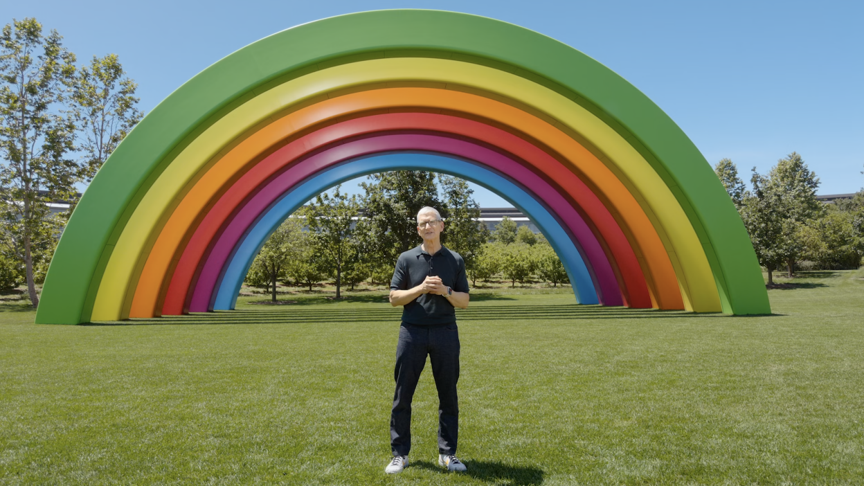Apple CEO Tim Cook standing in front of a rainbow on Apple campus.